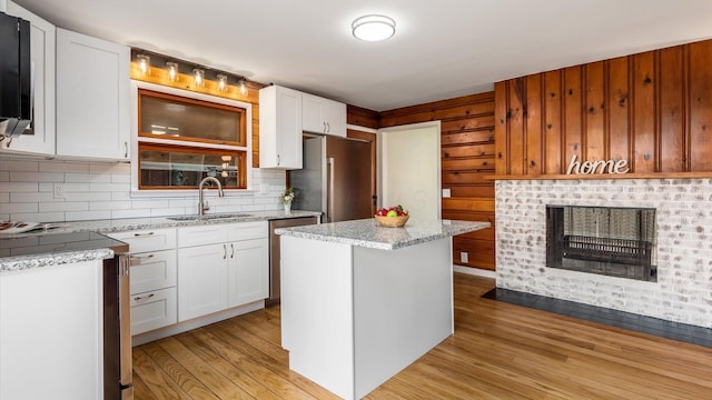 255 S Preston St, Centerburg, OH 43011 - kitchen with a sink, stainless steel appliances, light wood-type flooring, white cabinets, and wooden walls