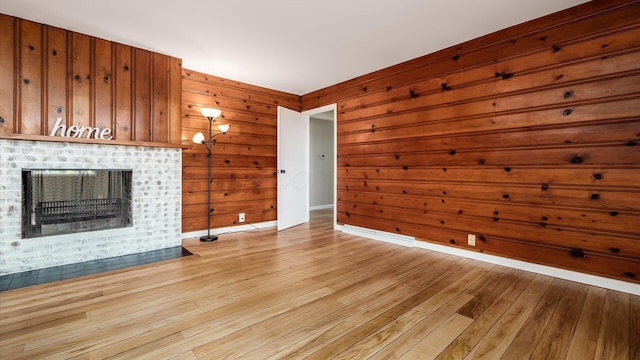 255 S Preston St, Centerburg, OH 43011 - unfurnished living room featuring light wood-style floors, a brick fireplace, wooden walls, and baseboards