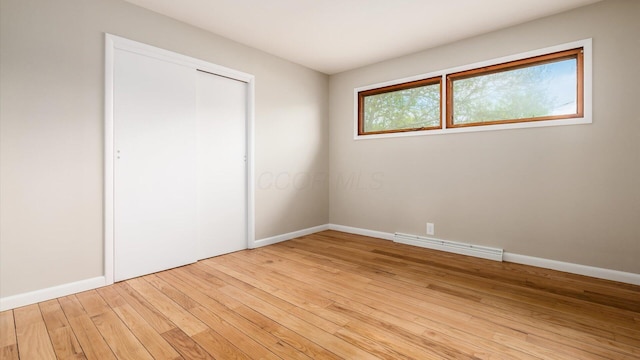 255 S Preston St, Centerburg, OH 43011 - unfurnished bedroom with light wood-style flooring, baseboards, a closet, and a baseboard heating unit