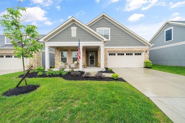 6678 Trinity Mist Way, Delaware, OH 43015 - view of front facade with covered porch, stone siding, driveway, a garage, and a front lawn