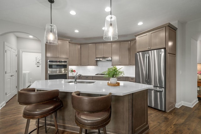 6678 Trinity Mist Way, Delaware, OH 43015 - kitchen featuring stainless steel appliances, a sink, washing machine and dryer, under cabinet range hood, and arched walkways
