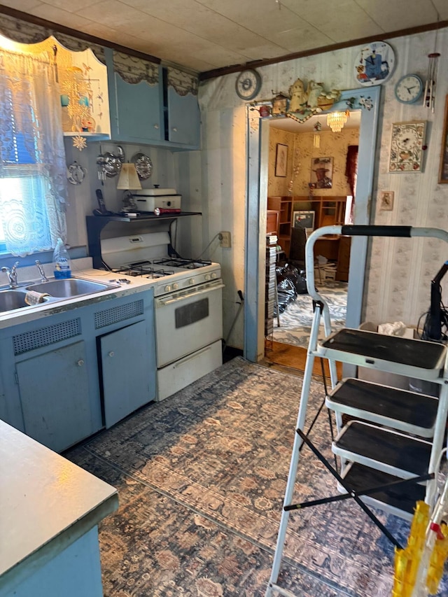 kitchen with white range with gas cooktop, a sink, blue cabinetry, and light countertops