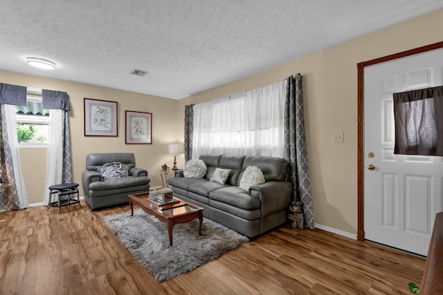 living room featuring a textured ceiling, wood finished floors, and baseboards