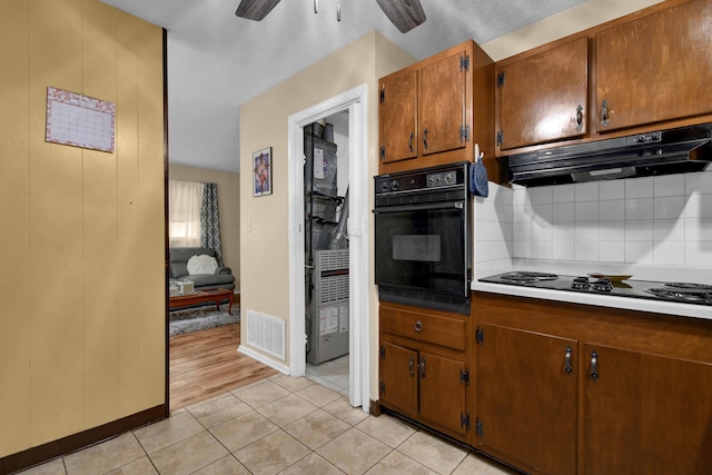 kitchen with black appliances, under cabinet range hood, backsplash, ceiling fan, and brown cabinetry
