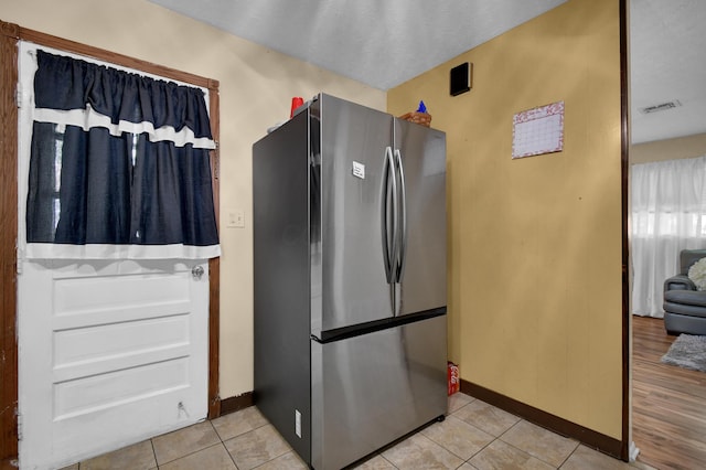 kitchen featuring freestanding refrigerator, baseboards, and light tile patterned flooring