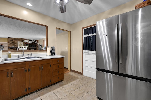 kitchen with freestanding refrigerator, a sink, light countertops, a ceiling fan, and light tile patterned floors