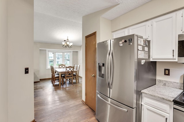 7170 Daugherty Dr, Reynoldsburg, OH 43068 - kitchen featuring stainless steel appliances, a chandelier, white cabinets, light wood-style flooring, and a textured ceiling