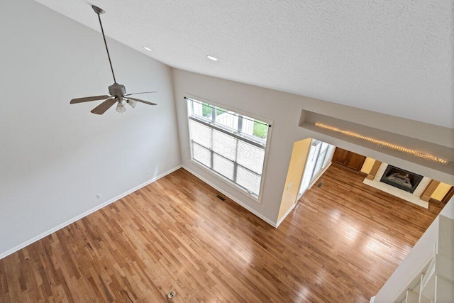 6575 Wensley Ct, Westerville, OH 43082 - unfurnished living room featuring a textured ceiling, vaulted ceiling, wood finished floors, baseboards, and a ceiling fan