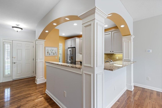 6575 Wensley Ct, Westerville, OH 43082 - kitchen featuring stainless steel fridge with ice dispenser, decorative columns, a peninsula, arched walkways, and light stone counters