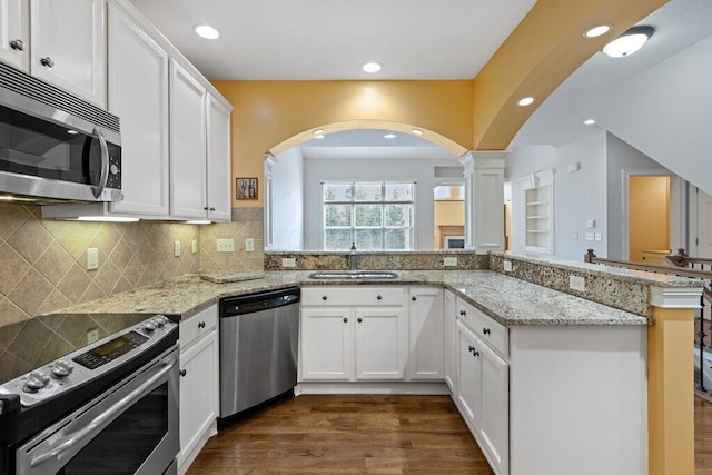 6575 Wensley Ct, Westerville, OH 43082 - kitchen featuring stainless steel appliances, a sink, arched walkways, white cabinets, and recessed lighting