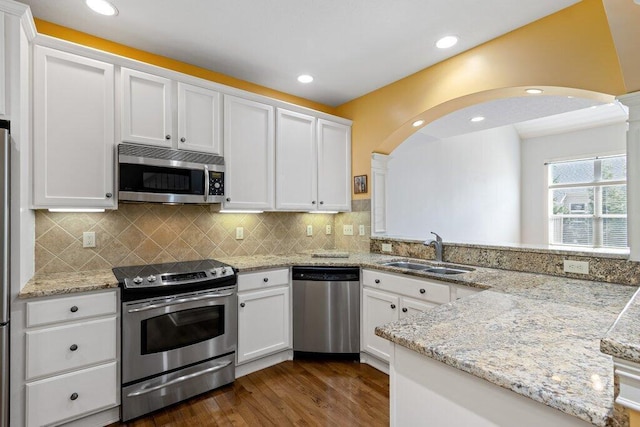 6575 Wensley Ct, Westerville, OH 43082 - kitchen featuring stainless steel appliances, a sink, arched walkways, dark wood-style floors, and white cabinets