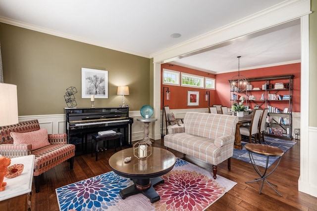 living area featuring hardwood / wood-style flooring, ornamental molding, a wainscoted wall, a chandelier, and a decorative wall