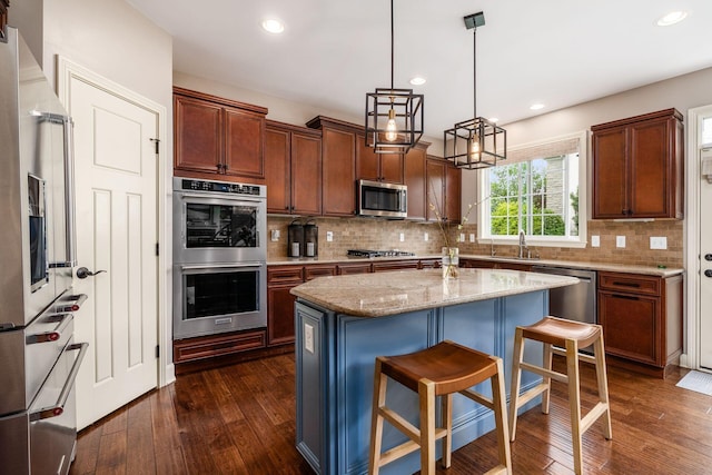 kitchen with stainless steel appliances, a sink, dark wood-style flooring, decorative backsplash, and light stone counters