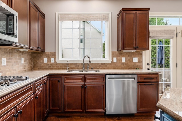 kitchen featuring appliances with stainless steel finishes, a sink, tasteful backsplash, and dark wood-style flooring