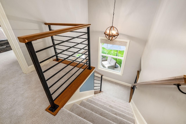 stairs featuring a chandelier, carpet flooring, and baseboards
