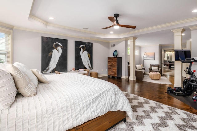 bedroom featuring decorative columns, multiple windows, wood finished floors, ornamental molding, and baseboards