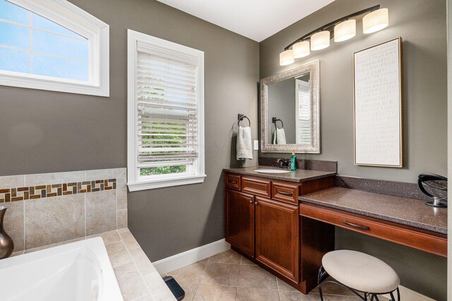 bathroom featuring a bath, vanity, baseboards, and tile patterned floors