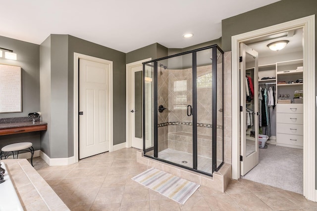 bathroom featuring a stall shower, baseboards, tile patterned flooring, and a spacious closet