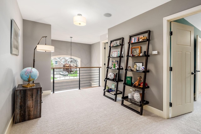 hallway with carpet flooring, a chandelier, and baseboards