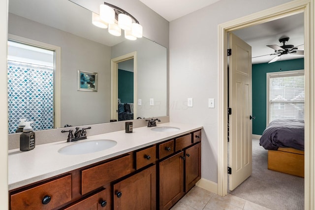 ensuite bathroom featuring double vanity, tile patterned flooring, a ceiling fan, and baseboards