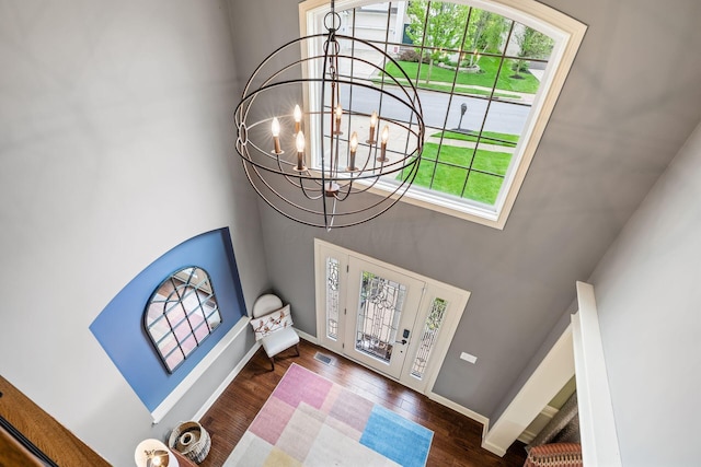 foyer with healthy amount of natural light, a high ceiling, a chandelier, wood finished floors, and baseboards