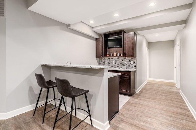 indoor wet bar featuring tasteful backsplash, baseboards, and recessed lighting