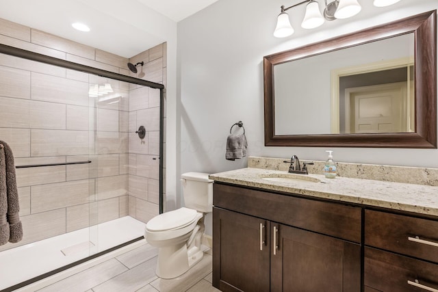bathroom with toilet, a shower stall, vanity, and baseboards