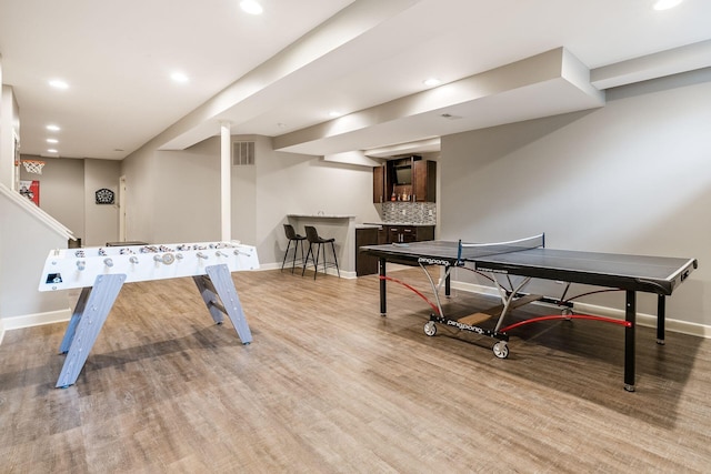 game room with bar with sink, baseboards, light wood-type flooring, and recessed lighting
