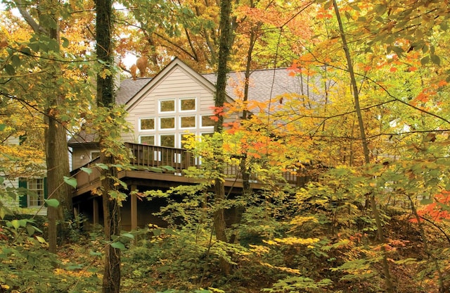 rear view of house with roof with shingles and a wooden deck