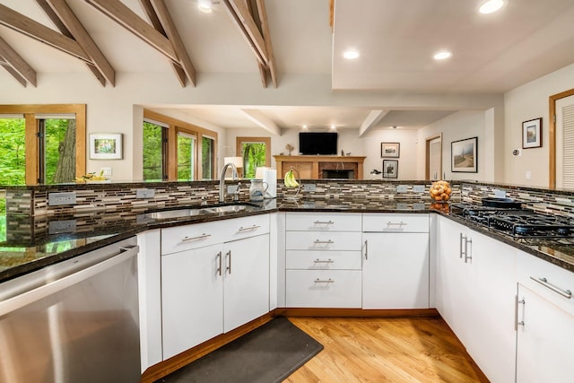 kitchen featuring stainless steel dishwasher, a sink, tasteful backsplash, recessed lighting, and light wood-style flooring
