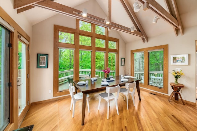 dining room with beamed ceiling, light wood-style floors, baseboards, and high vaulted ceiling