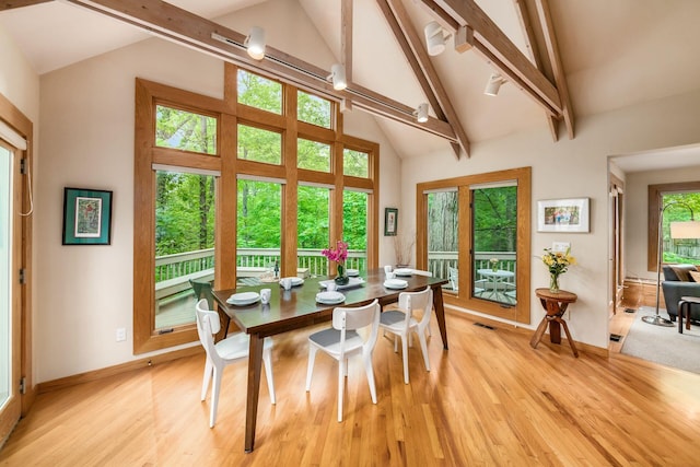 dining area with light wood-style floors, beamed ceiling, baseboards, and high vaulted ceiling