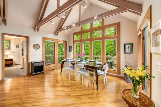 dining area with beamed ceiling, light wood-style floors, high vaulted ceiling, and baseboards