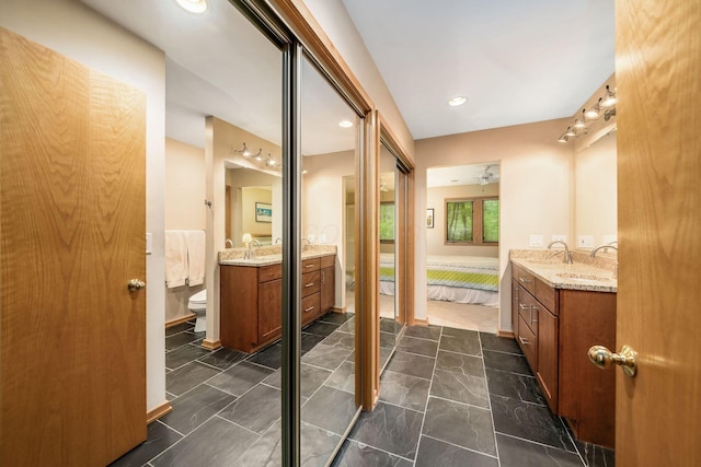 ensuite bathroom with two vanities, marble look tile flooring, toilet, and baseboards