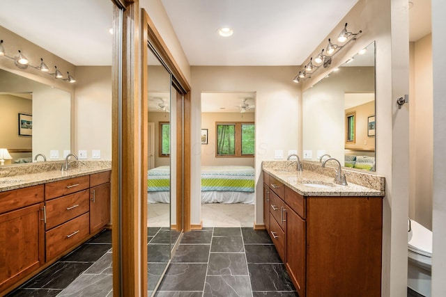 full bathroom featuring two vanities, ensuite bath, ceiling fan, and baseboards