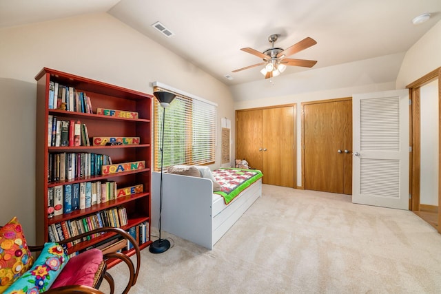 bedroom with two closets, carpet flooring, lofted ceiling, and ceiling fan