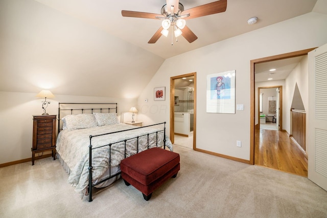 bedroom featuring lofted ceiling, light colored carpet, baseboards, ensuite bathroom, and a ceiling fan