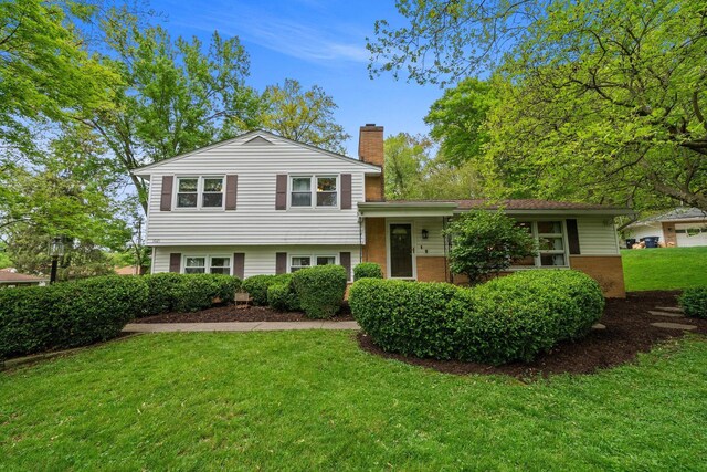 split level home with a chimney and a front lawn