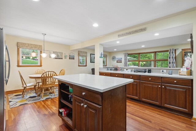 kitchen with light wood-type flooring, light countertops, hanging light fixtures, a center island, and recessed lighting