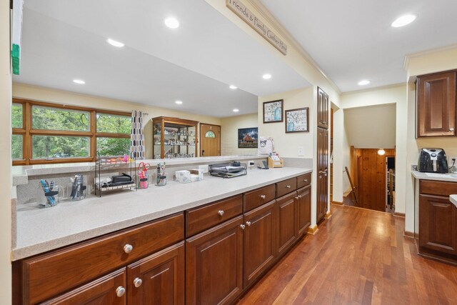 kitchen featuring light countertops, wood finished floors, recessed lighting, and crown molding
