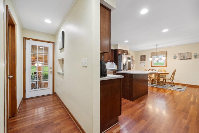 kitchen featuring stainless steel fridge with ice dispenser, a center island, light countertops, wood finished floors, and baseboards