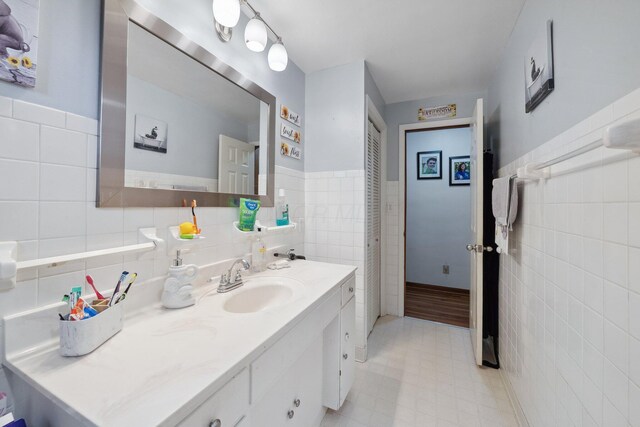 bathroom featuring tile walls, vanity, and a wainscoted wall