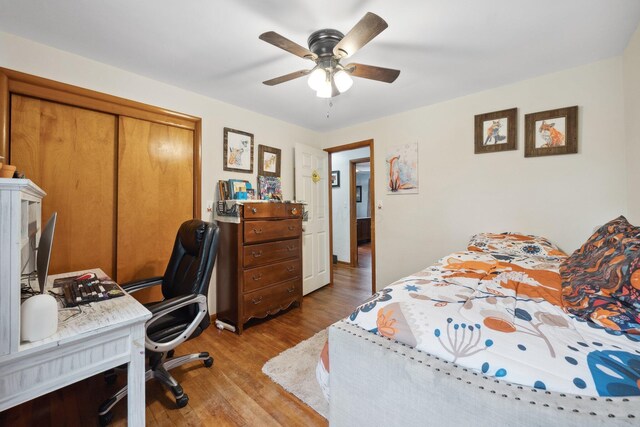 bedroom with wood finished floors, a closet, a desk, and ceiling fan