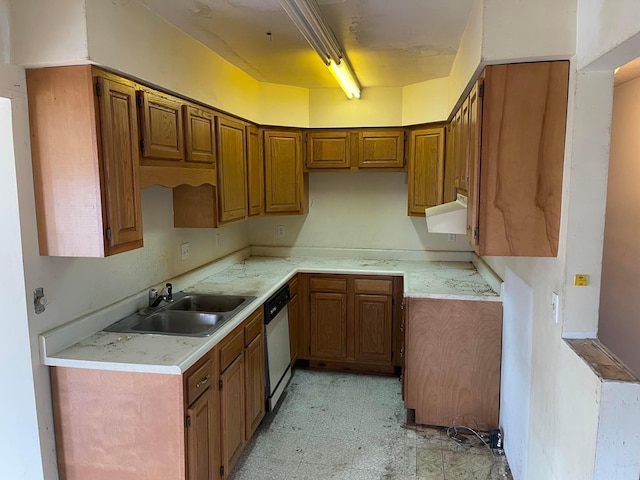 kitchen featuring a sink, dishwasher, light countertops, light floors, and brown cabinets