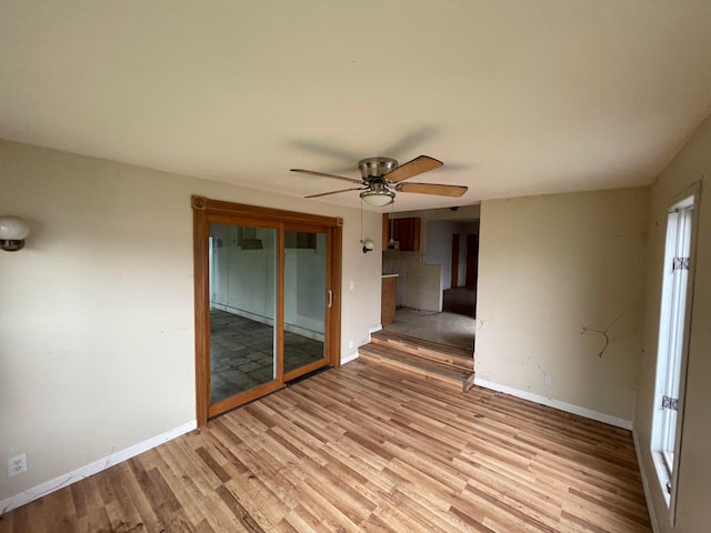 unfurnished room with a ceiling fan, light wood finished floors, and baseboards