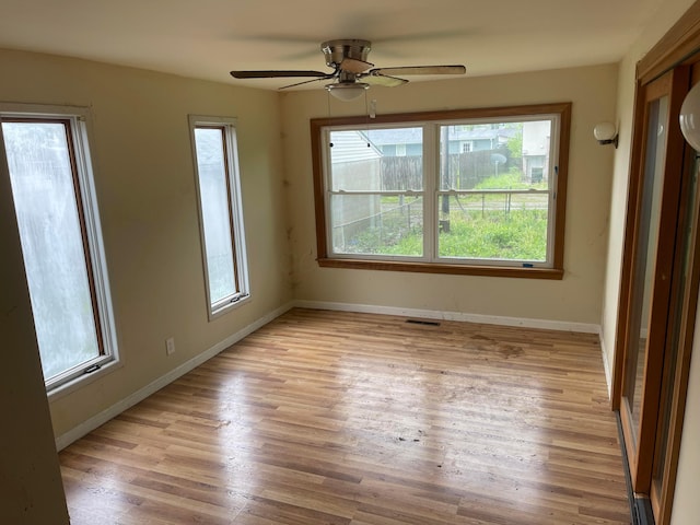 empty room with light wood finished floors, baseboards, and a ceiling fan