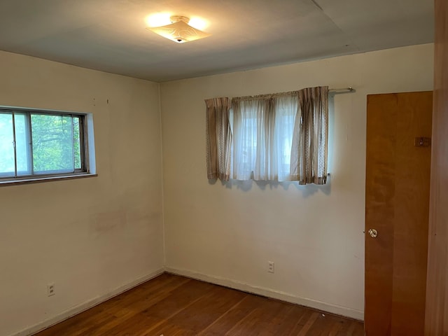 unfurnished room with dark wood-type flooring and baseboards