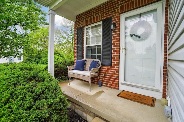view of exterior entry featuring covered porch and brick siding