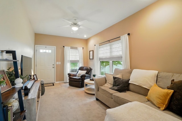living area featuring light colored carpet, a ceiling fan, and baseboards