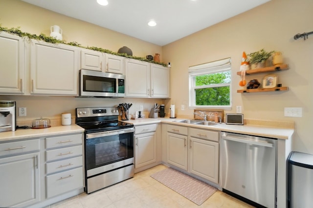 kitchen with appliances with stainless steel finishes, a sink, light countertops, open shelves, and recessed lighting